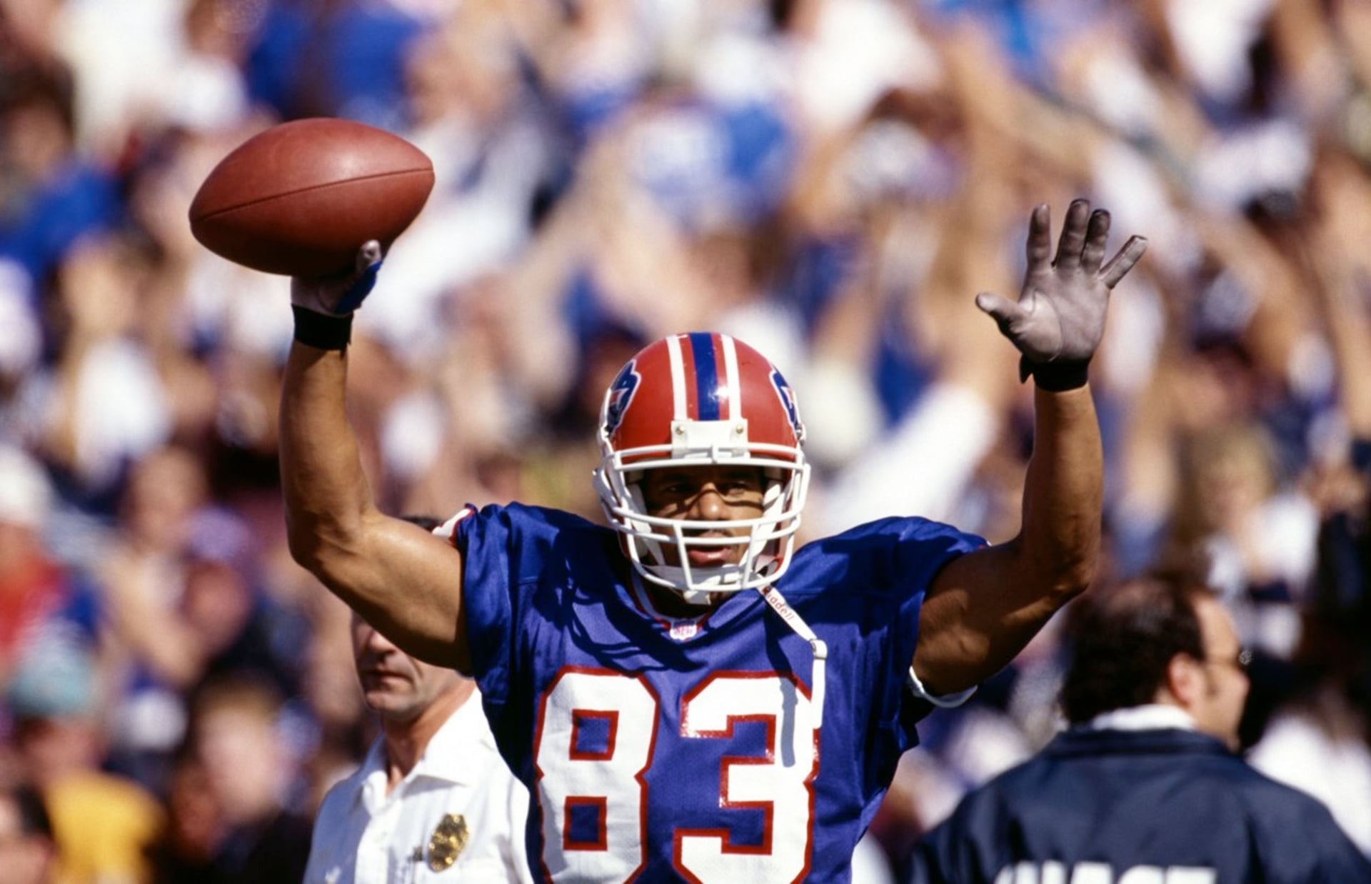 Andre Reed in his Buffalo Bills #83 jersey, arms raised holding the ball aloft in celebration