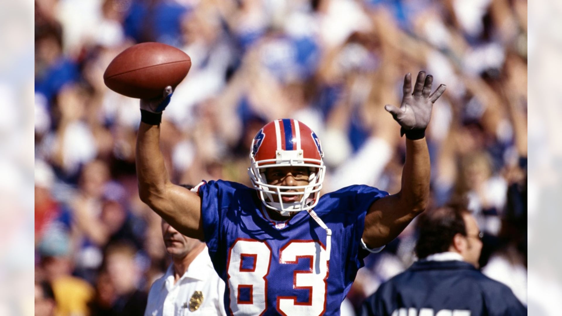 Andre Reed in his Buffalo Bills #83 jersey, arms raised holding the ball aloft in celebration