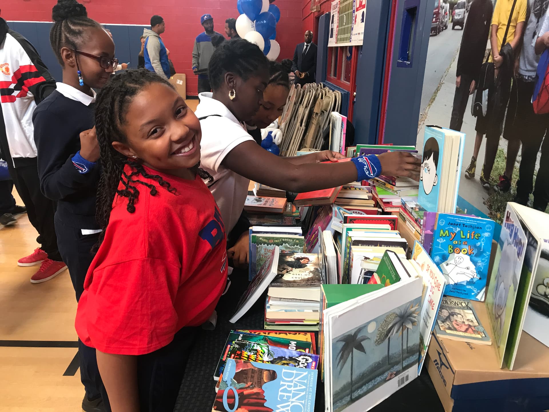 Kids browse a table of donated books in a Boys & Girls Club gym