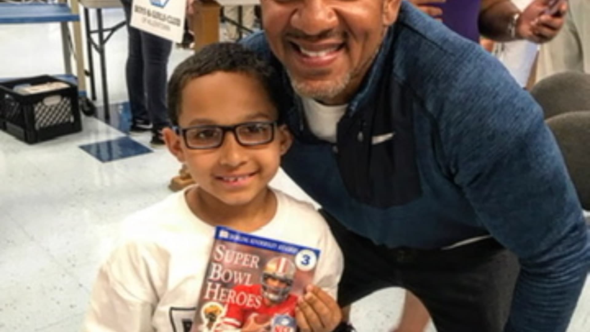 Andre Reed with a young reader holding a book at a Boys & Girls Club