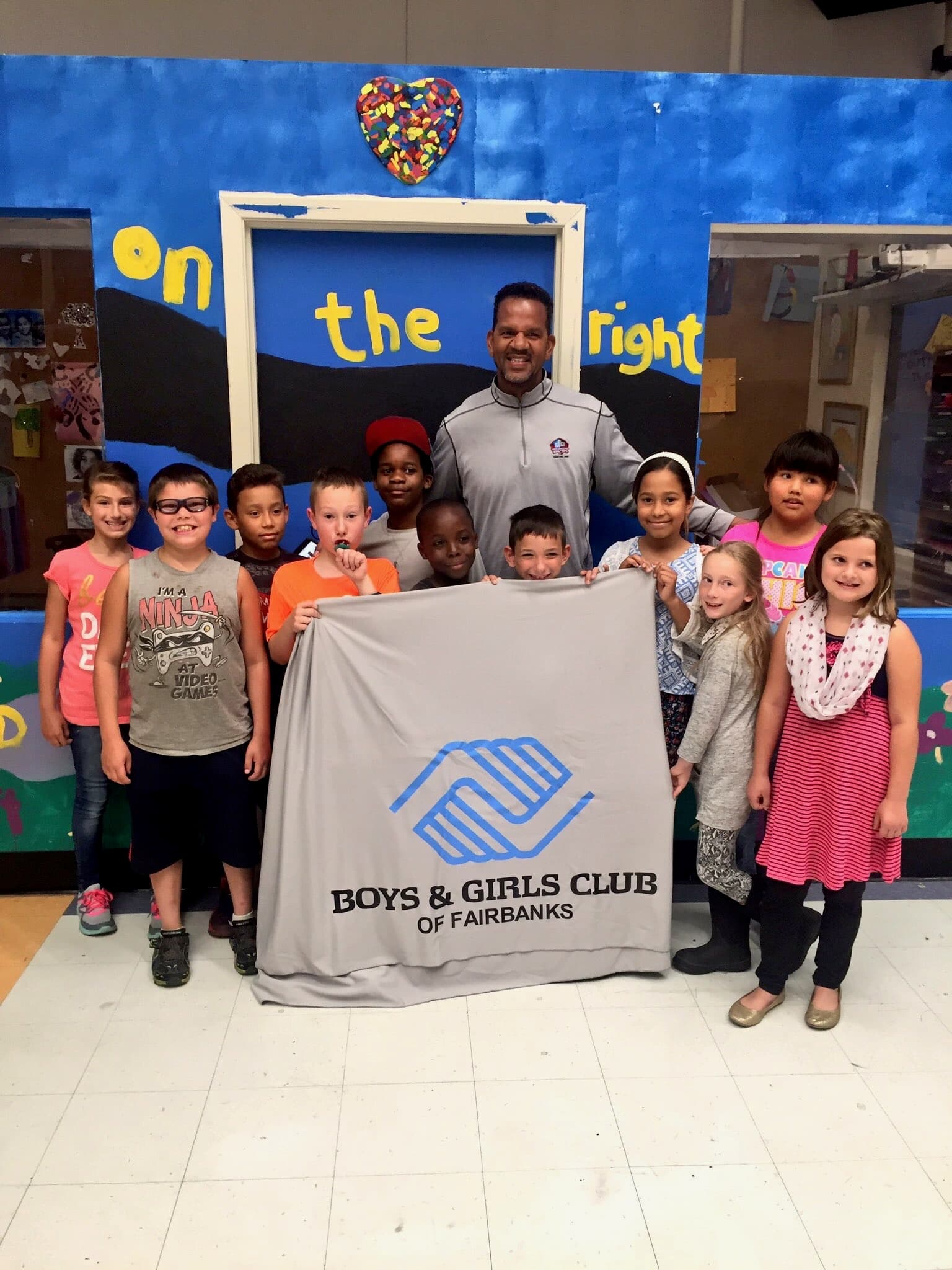 Andre Reed with a large group of kids holding a Boys & Girls Club of Fairbanks banner