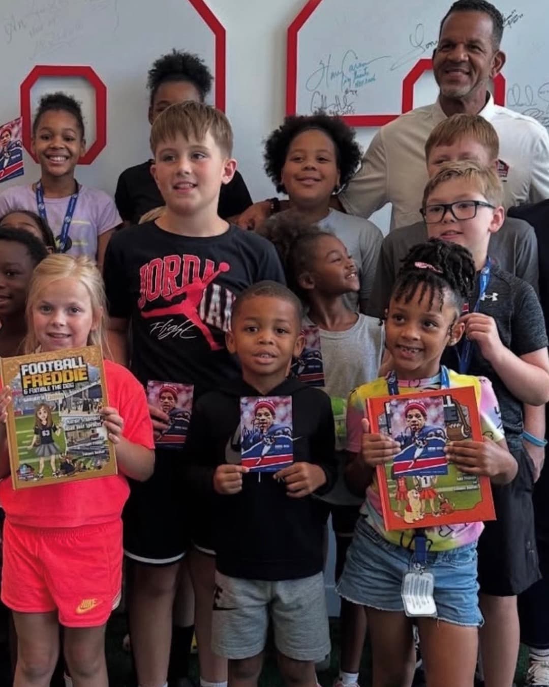 Andre Reed with a group of Lehigh Valley kids holding Football Freddie books