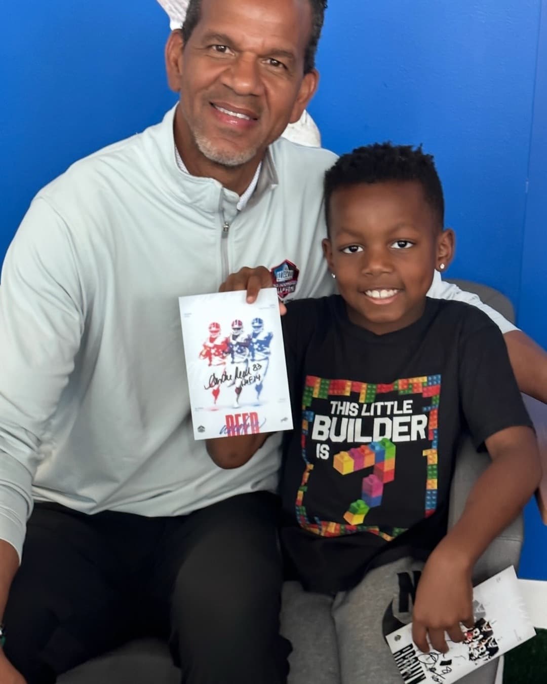 Andre Reed holds up a signed Hall of Fame photo card with a young fan