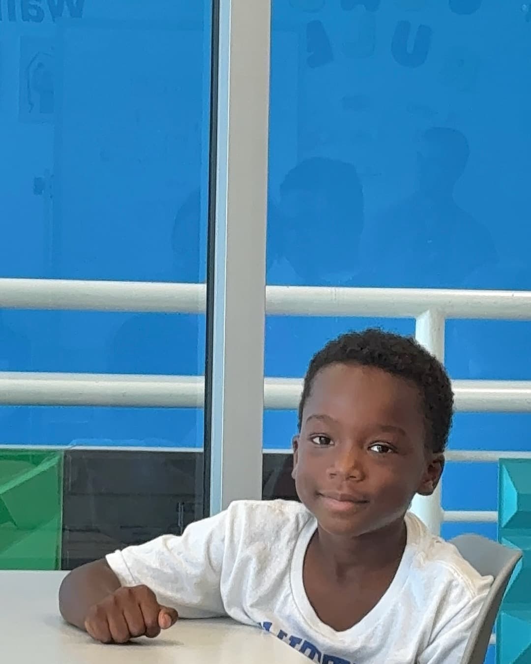 Boy reads inside a Reed-branded BGCA reading room with blue glass partitions