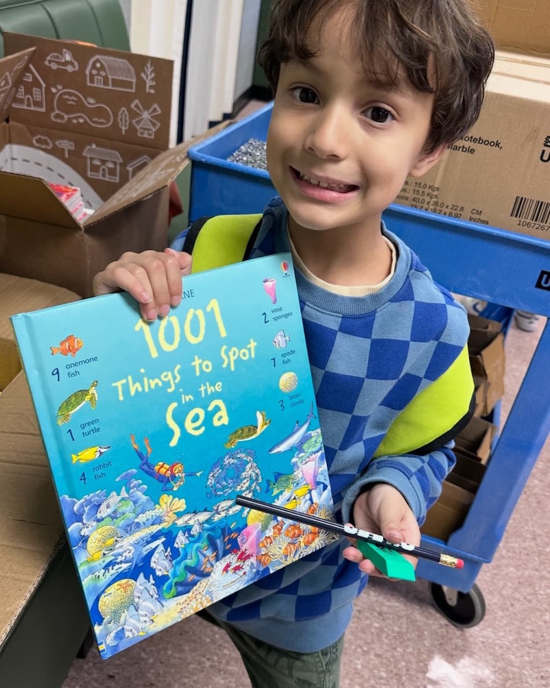 A boy proudly shows off "1001 Things to Spot in the Sea" in a Read with Reed reading room