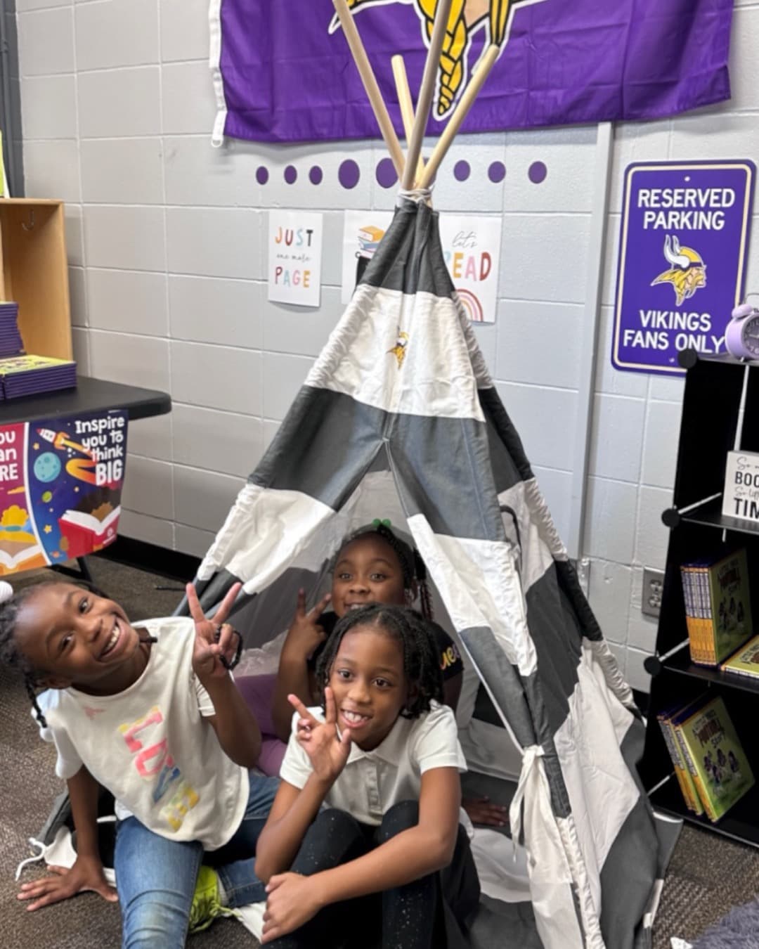 Three kids read inside a teepee reading tent at a Boys & Girls Club