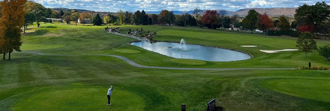 The championship course at Woodstone Country Club — fairway, fountain pond, and the Blue Mountains